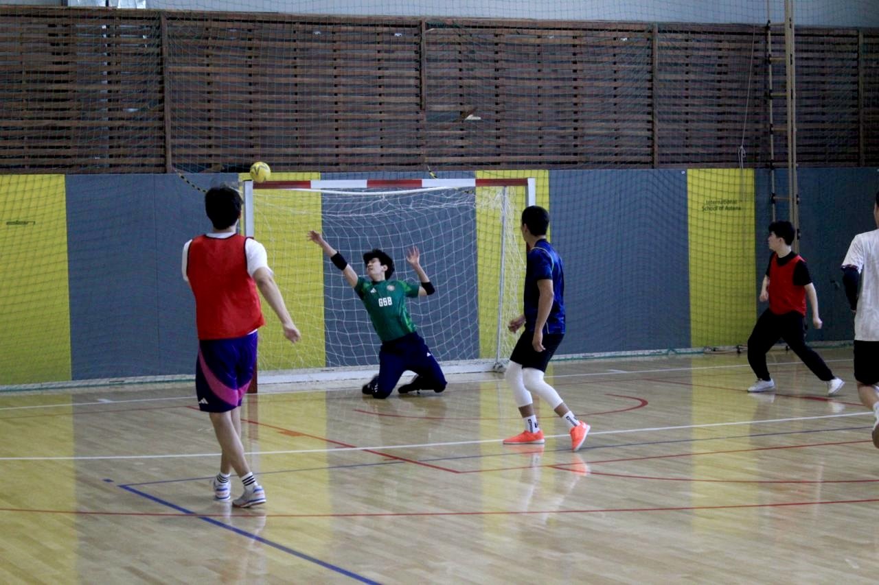 A futsal match with the ball flying toward the goal