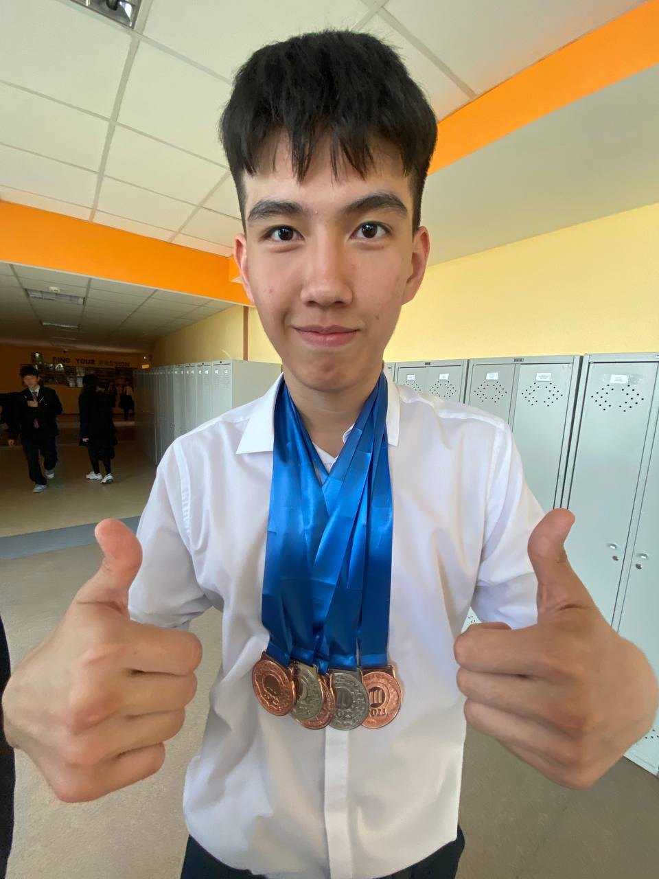 Wearing medals and giving two thumbs up in a school hallway